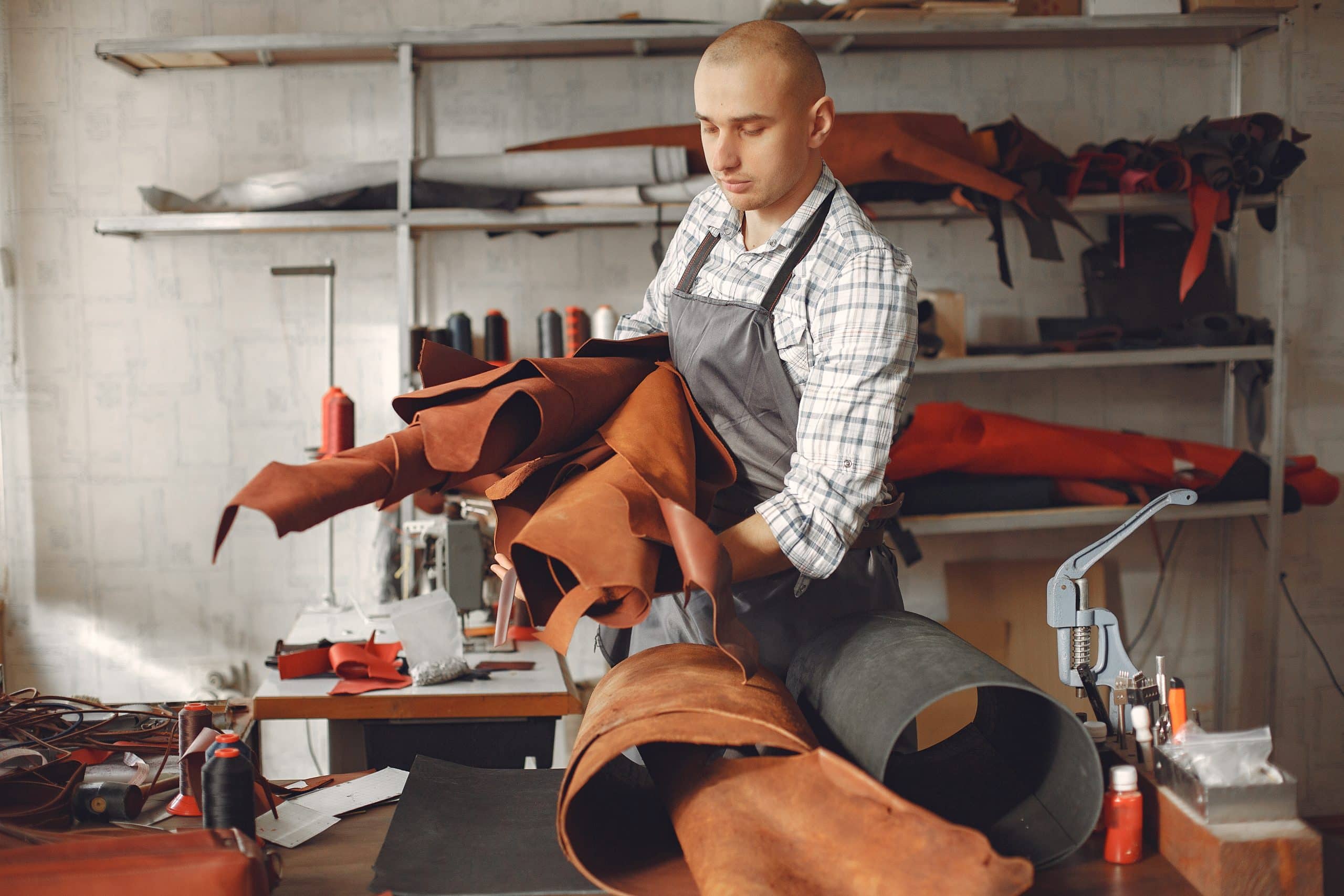 Man working with leather. Professional makes a belts. Man holds a factory in his hands